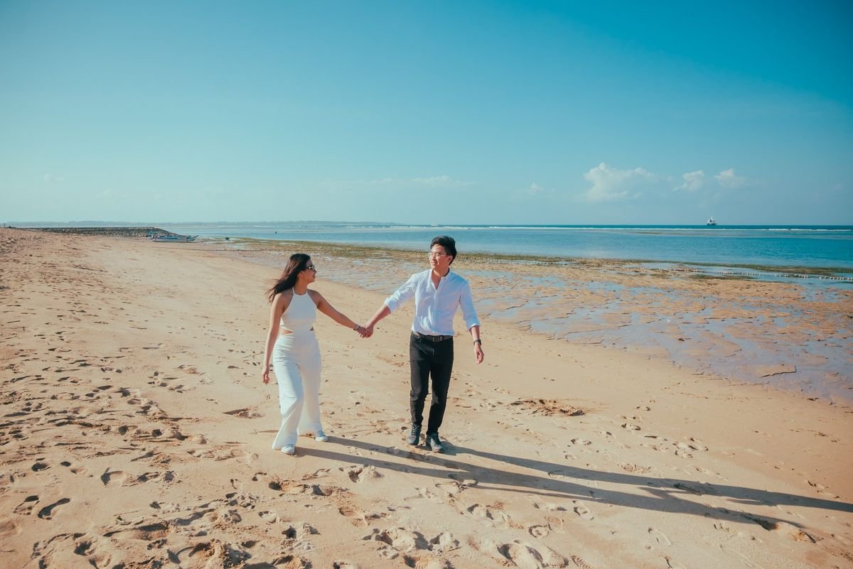 Joseph and Novilia walking hand in hand on a beach